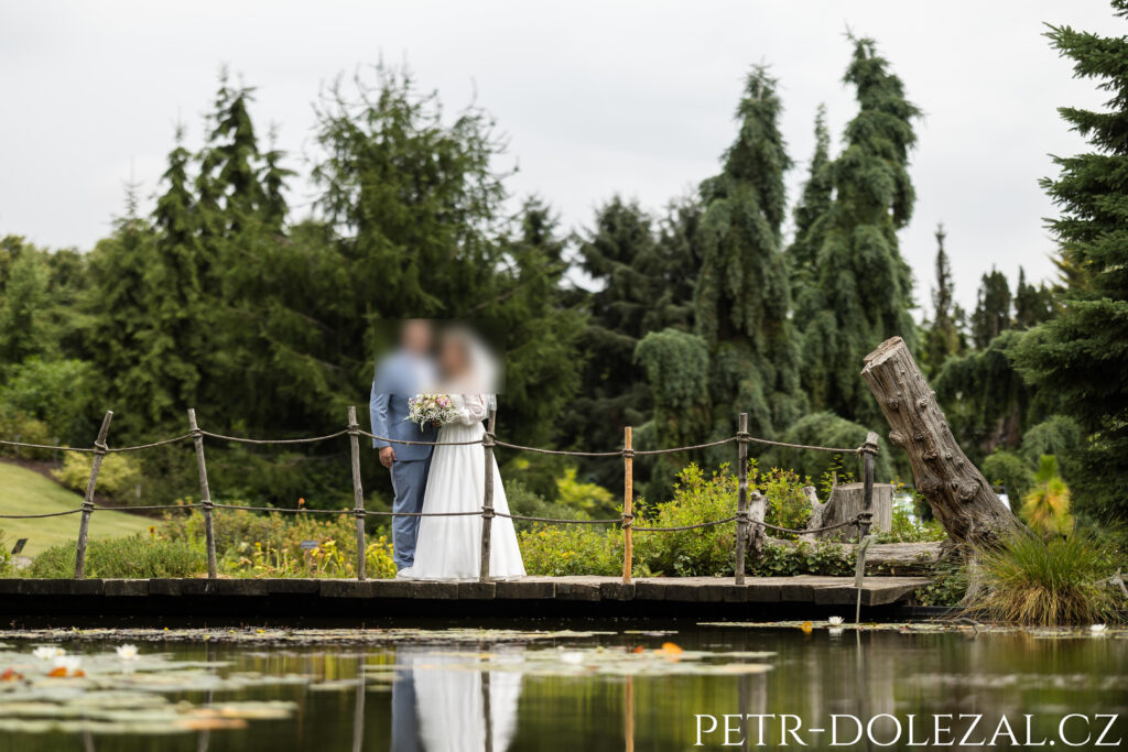 ženich s nevěstou na můstku nad vodní hladinou, ve které se zrcadlí