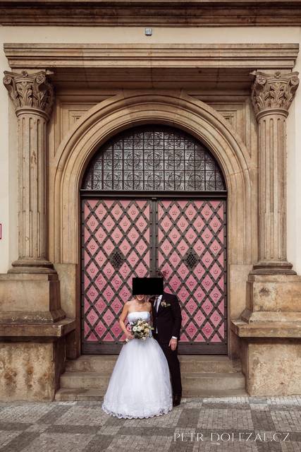Nevěsta a ženich před velkými zavřenými dveřmi