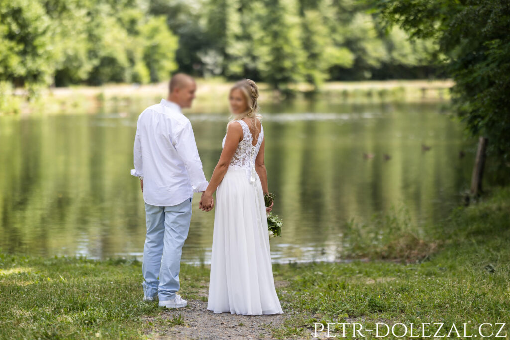 Novomanželé otočení zády u rybníka