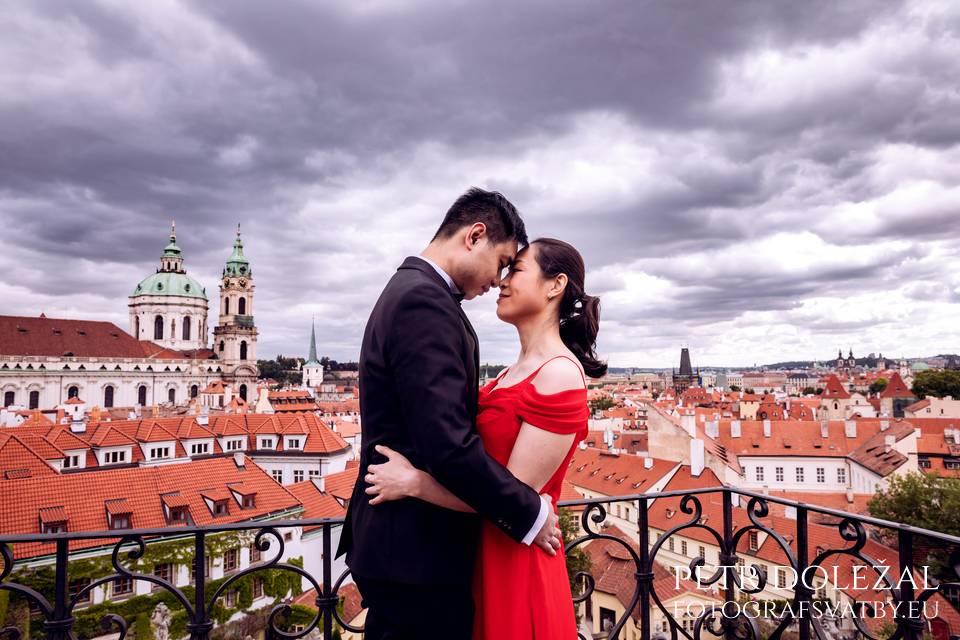 Hugging couple on top of Vrtba garden with prague church and roofs in background