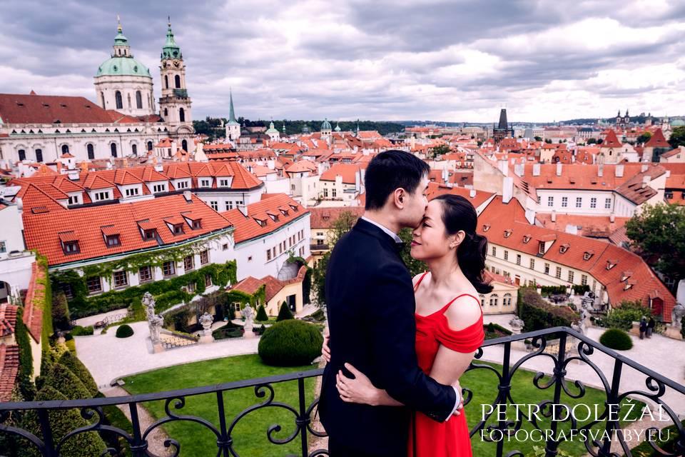 Man kissing his girlfriend's forehead with prague roofs in the background