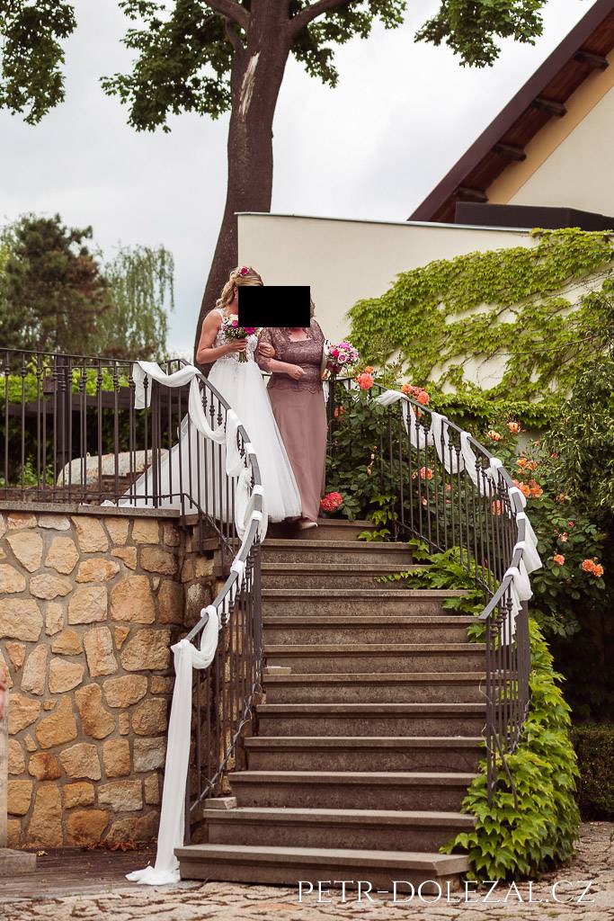 Nevěsta s maminkou přicházejí ze schodiště na úvodu svatebního obřadu, do té doby je nikdo neviděl