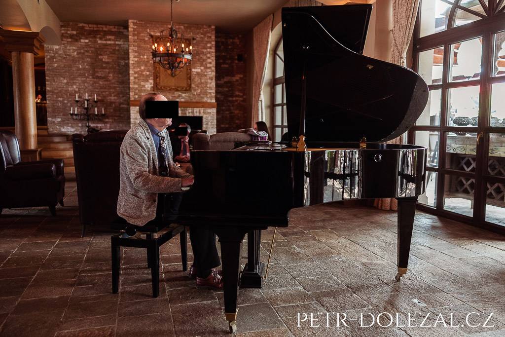 Klavírista hrající na křídlo při vítání svatebních hostů ve foyeru Park Hotelu Popovičky