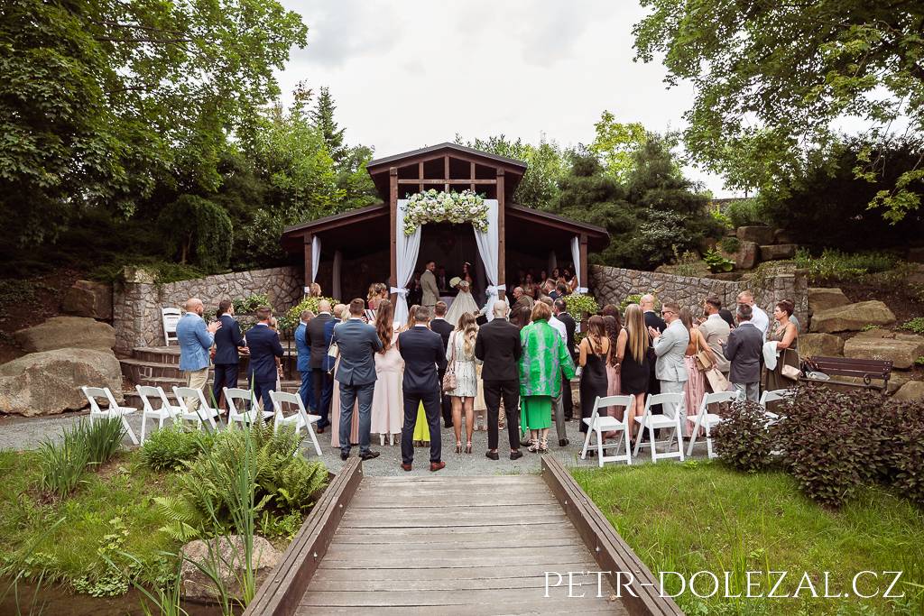 Svatební obřad v zahradním altánku, vyfocený zezadu