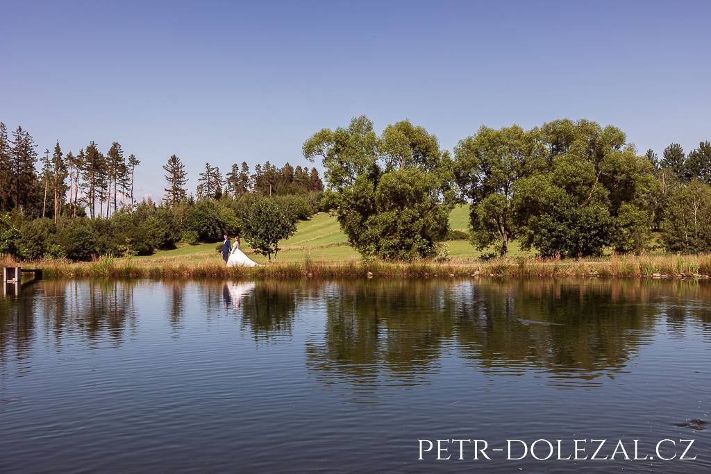 Ženich s nevěstou jdoucí po břehu rybníka