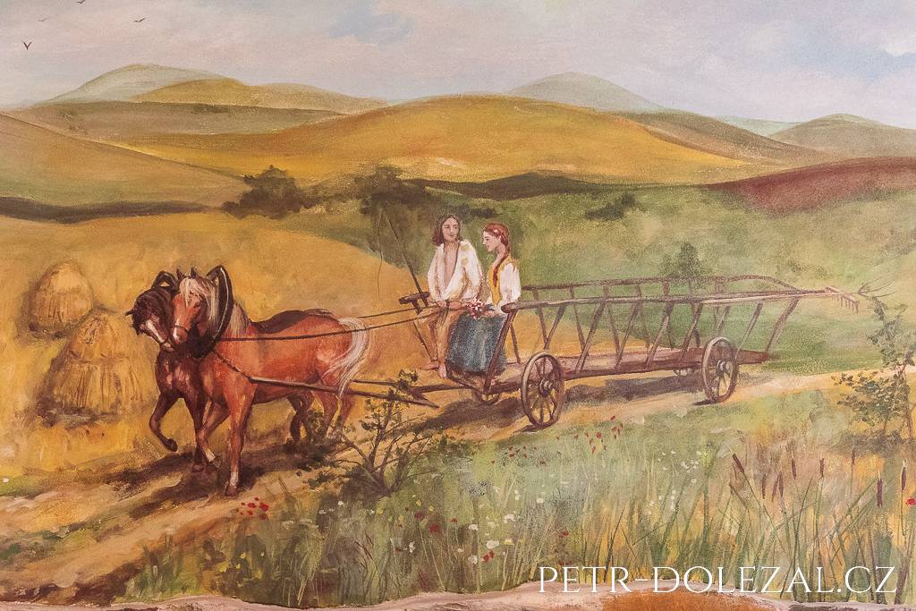Nástěnná malba zobrazující žebřiňák tažený dvěma koňmi, jedoucí po cestě mezi poli, na povoze sedí muž s bičem a dívka s květinou