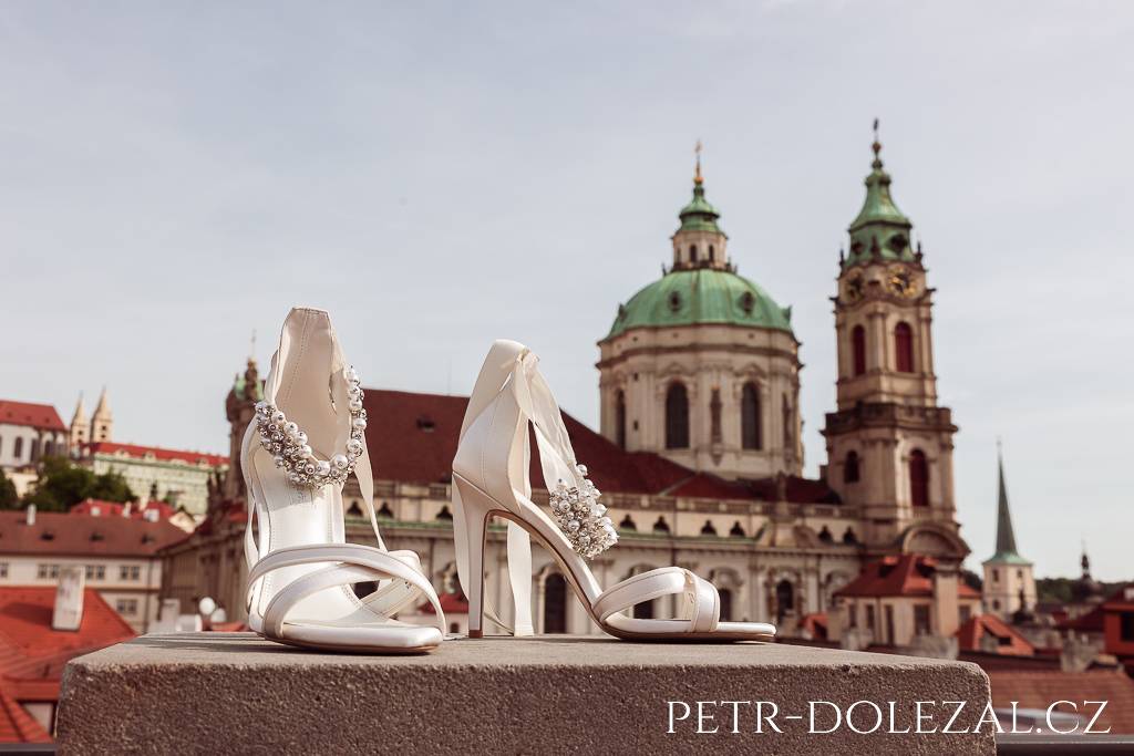 Střevíce nevěsty fotografované na střeše hotelu Aria proti kostelu sv. Mikuláše na Malé Straně v Praze