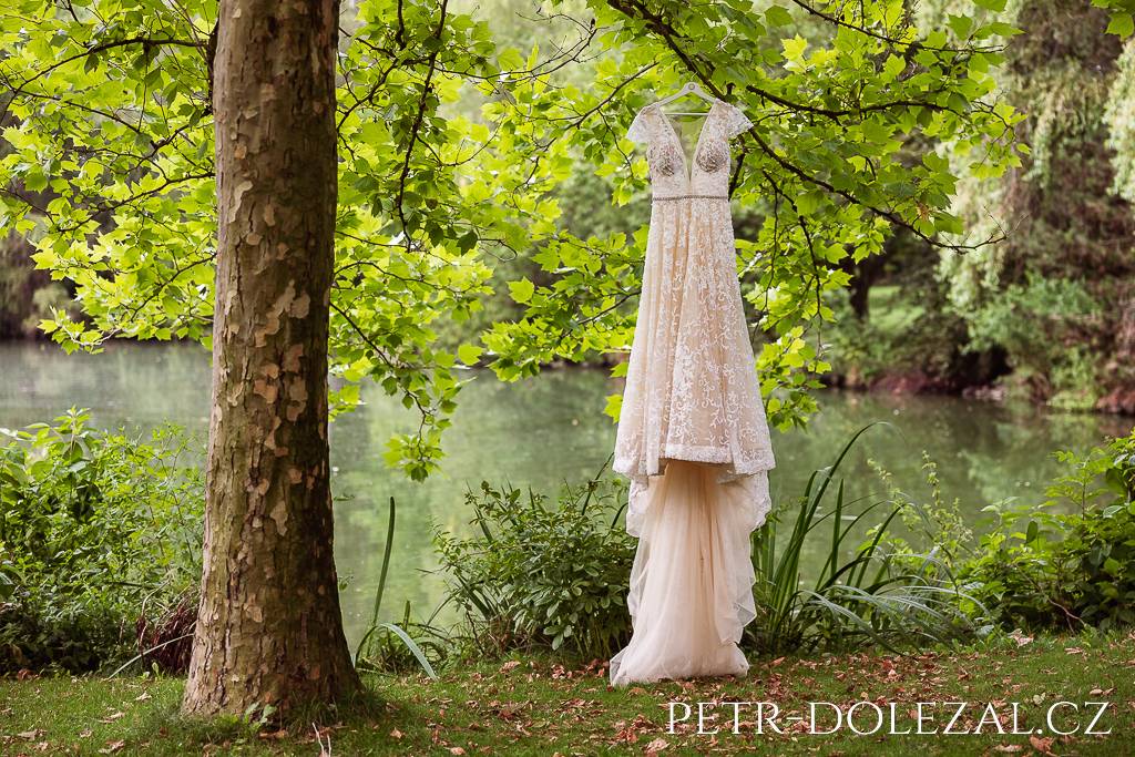 Šaty nevěsty zavěšené na větvi stromu před rybníkem