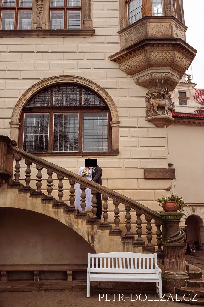Novomanželé na schodišti nádvoří zámku Průhonice, opírající se o schodištní balustrádu