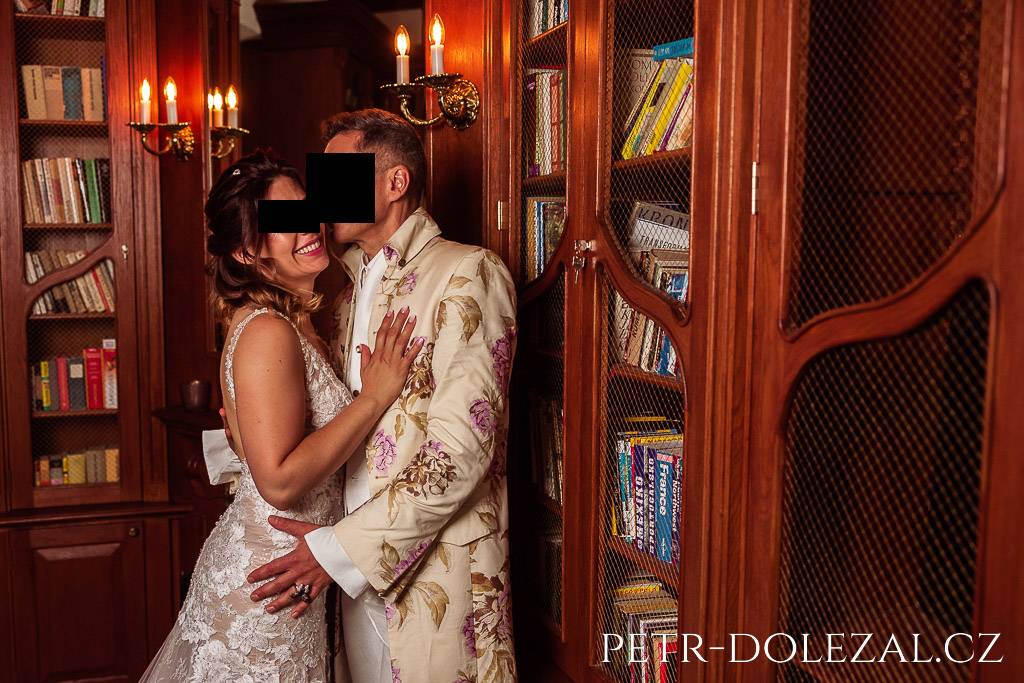 Objímající se nevěsta a ženich v knihovně zámku Trnová, velikost záběru: americký plán
