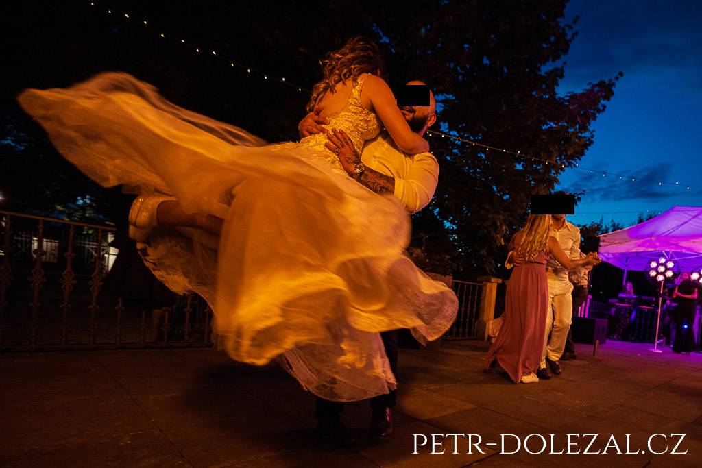 Tanec svatebčanů, nevěsta s rozevlátými šaty zvednutá mužem při tanci