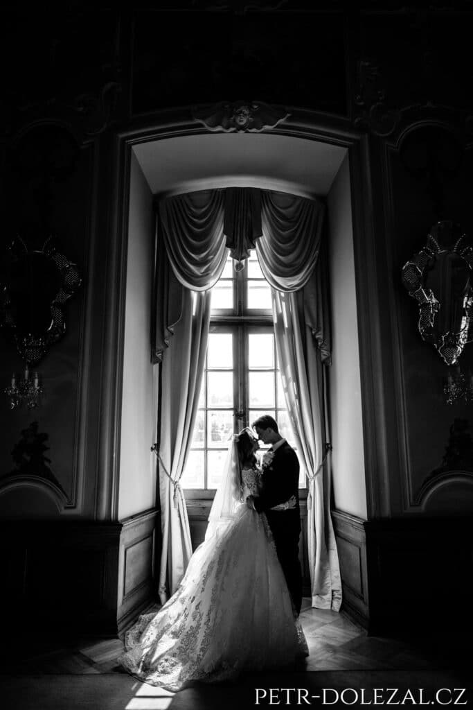 nevěsta a ženich před zámeckým oknem, černobílá fotografie