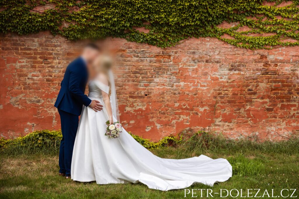 ženicha a nevěsta před oranžovou cihlovou zdí