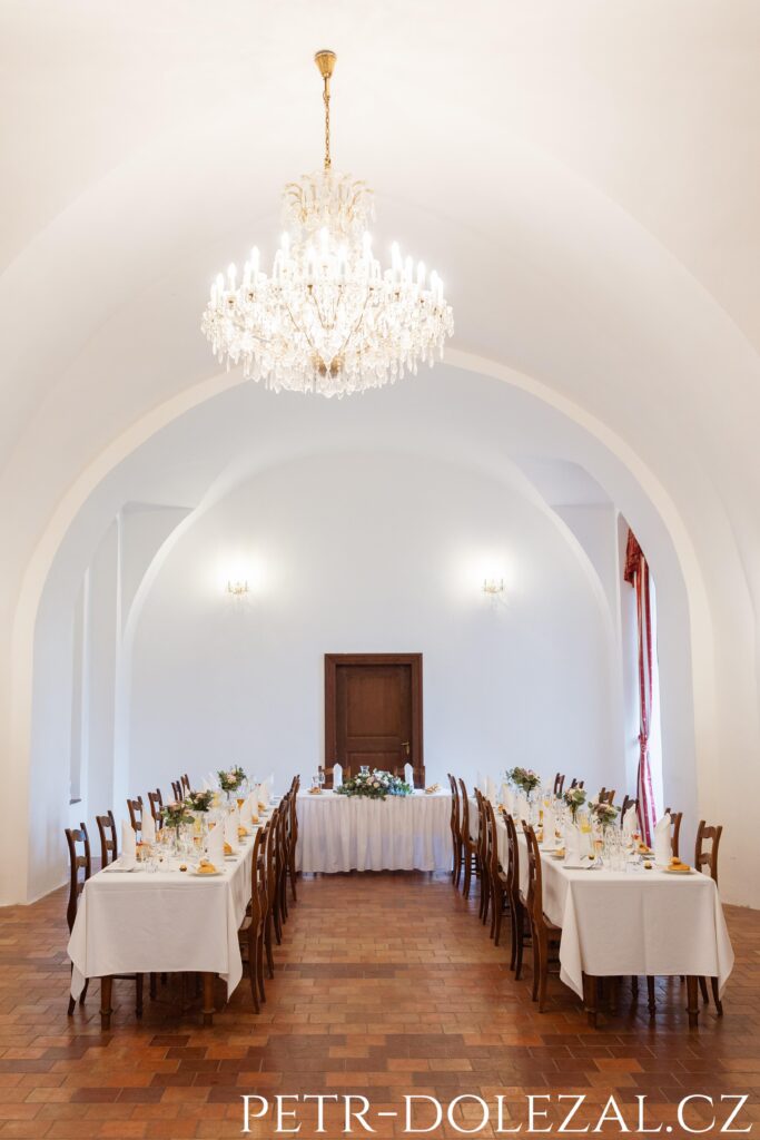 Sala terrena se stoly připravenými na svatební hostinu