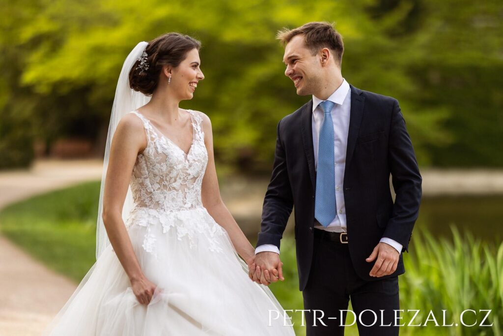 Nevěsta a ženich usmívající se na sebe a držící se za ruce