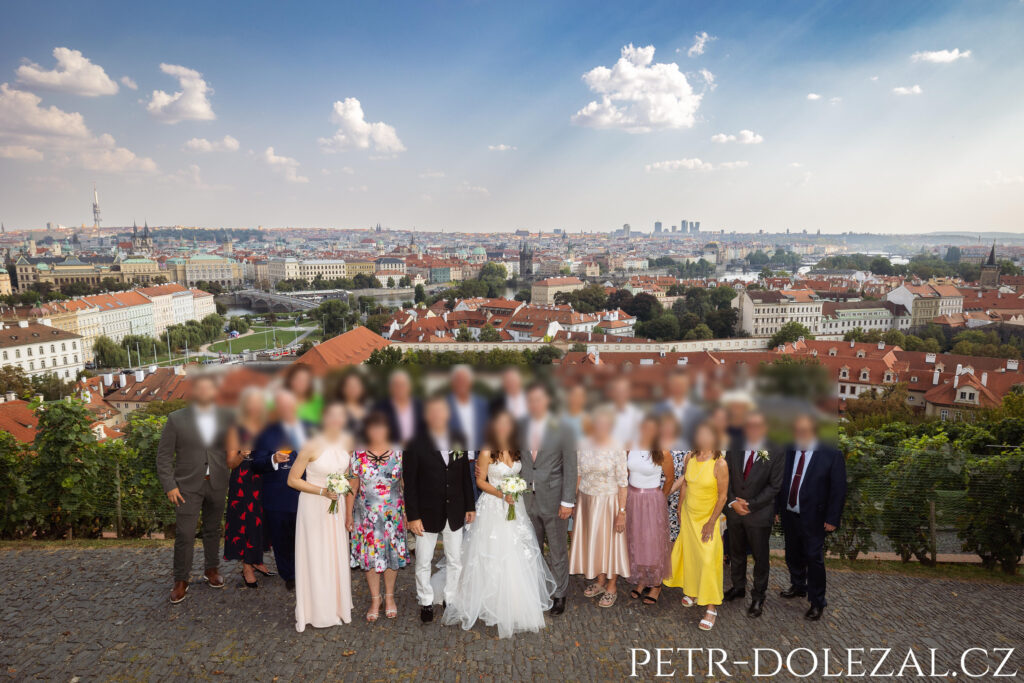 Skupinová fotografie 24 svatebních hostů na pozadí Prahy