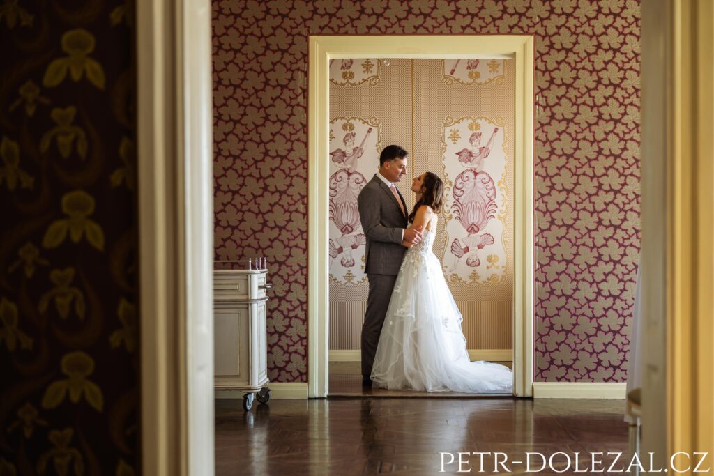Průhled třemi salónky k novomanželům v objetí