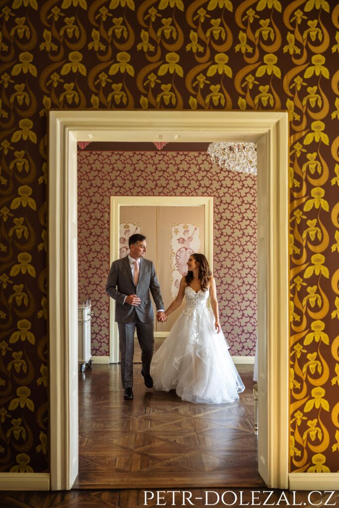 Ženich s nevěstou kráčející ruku v ruce přes salónky Villy Richter