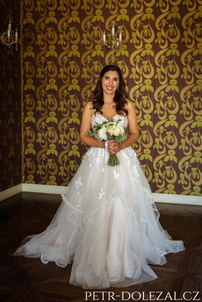 Nevěsta s kyticí - celek postavy, v pozadí tapety vnitřních salónku Villy Richter