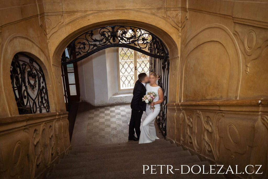 Novomanželé pod schodištěm zámku.