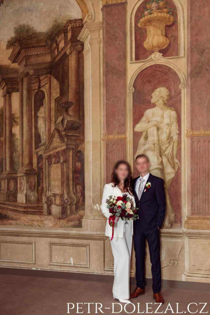 Novomanželé před malbami na zdi v obřadní síni zámku
